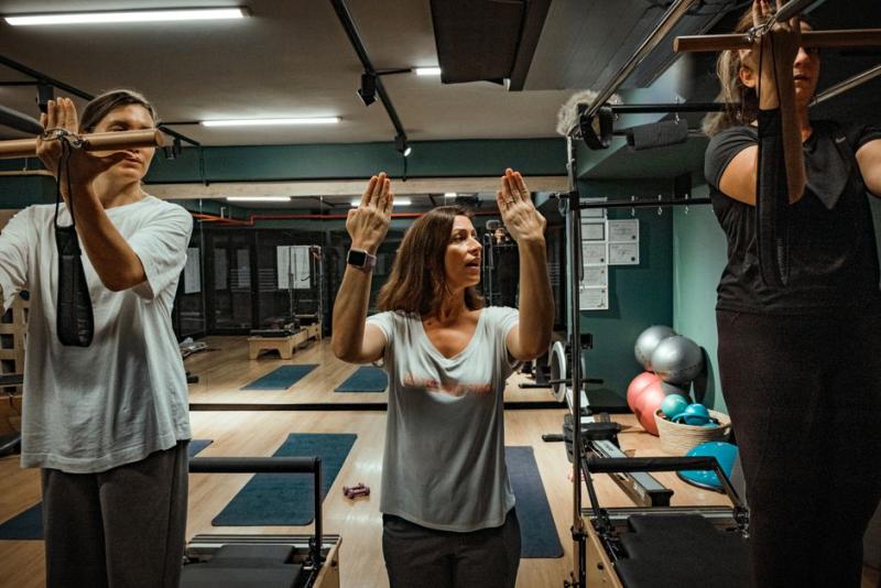 Instructora guiando una clase de pilates con máquinas en un estudio