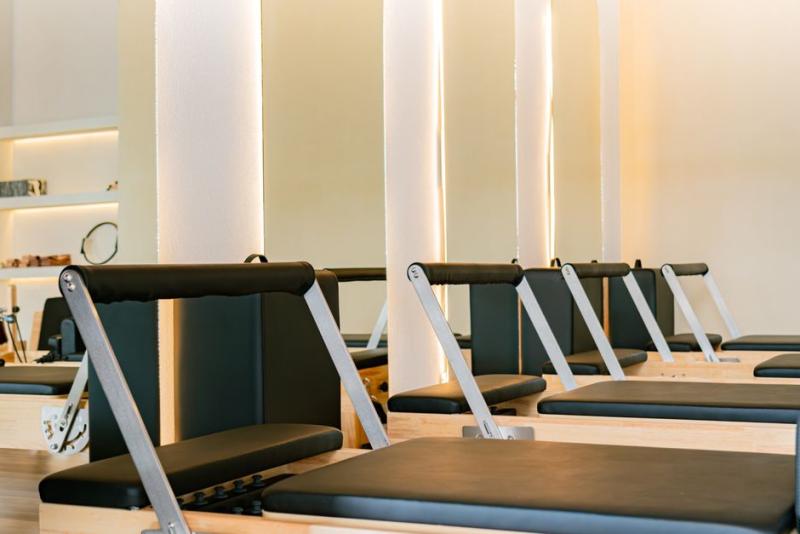 Estudio de pilates con máquinas reformer en fila, sala luminosa