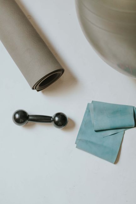 Colchoneta enrollada, banda elástica y pelota de pilates sobre una mesa