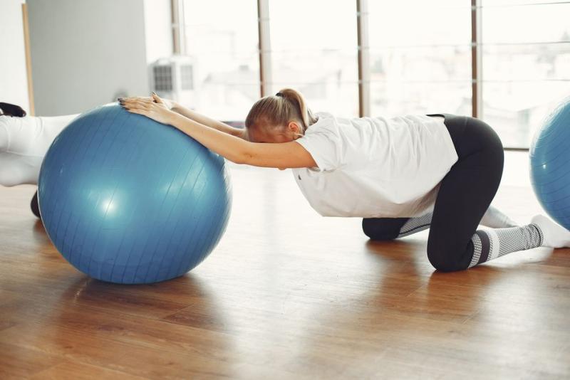 Mujer embarazada haciendo estiramientos de pilates con fitball en clase