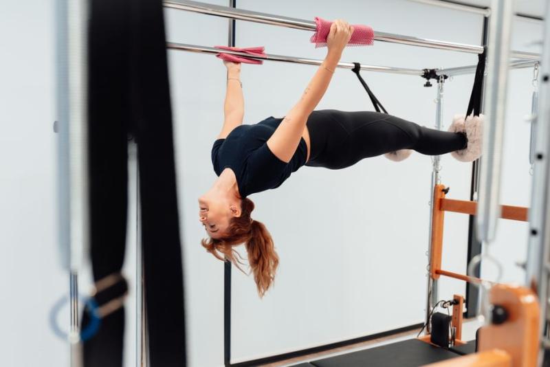 Mujer haciendo un ejercicio invertido en una máquina Cadillac de pilates