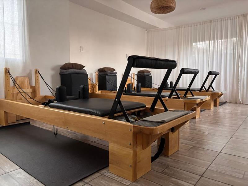Fila de máquinas reformer de pilates en un estudio luminoso