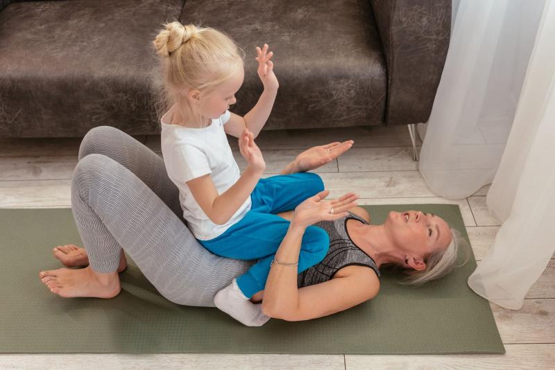 Abuela haciendo pilates en casa con su nieta sobre la esterilla